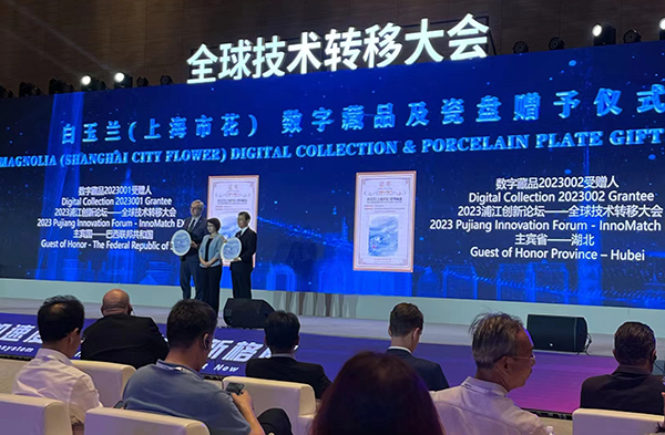 图为上海市政府秘书长向礼宾国和礼宾省赠予当代艺术家黄诗茹创作的白玉兰（上海市花）数字藏品和瓷盘